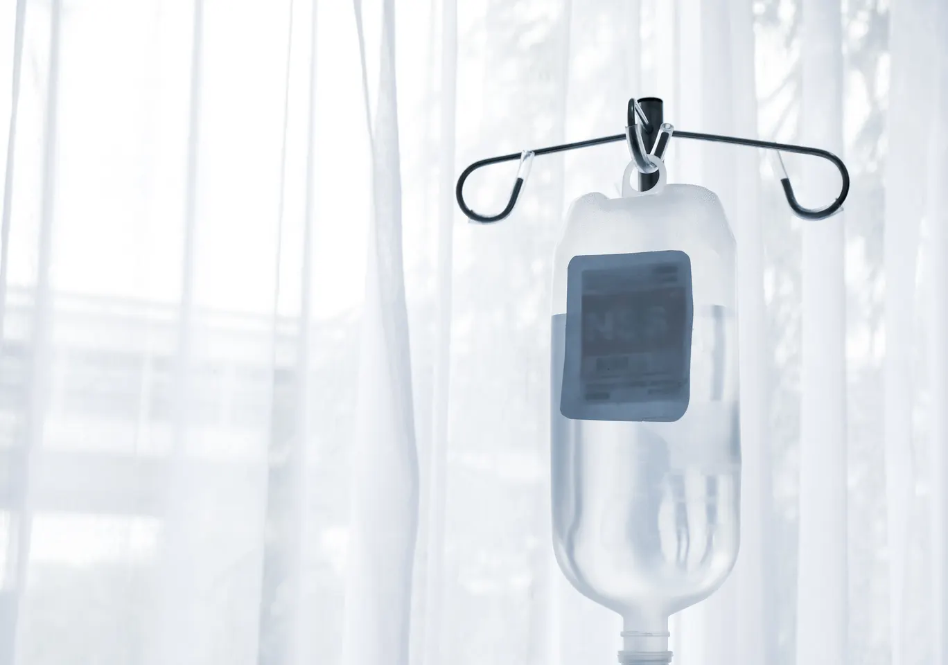 Kroplówki witaminowe Limanowa: butelka płynu infuzyjnego zawieszona przy oknie