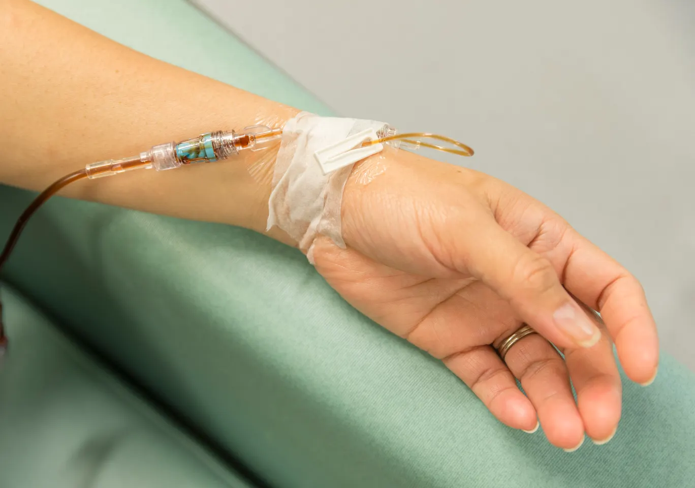 Kroplówki witaminowe Limanowa: dłoń z wenflonem i linią infuzyjną na podkładzie